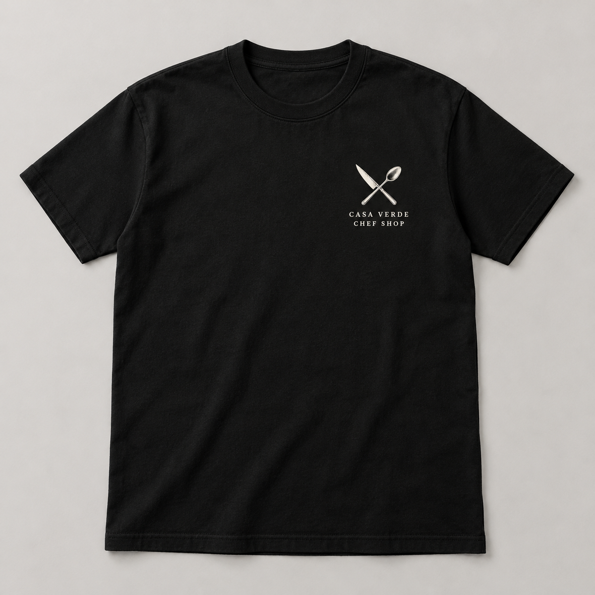 Chef tribute front — small crossed knife and spoon above the Casa Verde Chef Shop signature at the left chest. Approved garment design preview.