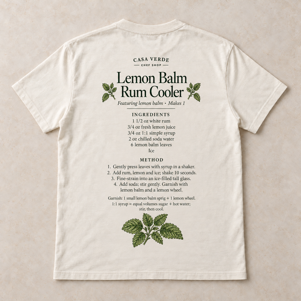 Lemon Balm Rum Cooler T-Shirt — approved individual back design preview with cocktail-recipe lettering and matching botanical illustration and the Casa Verde Chef Shop signature. Illustrative garment mockup, not a production master.