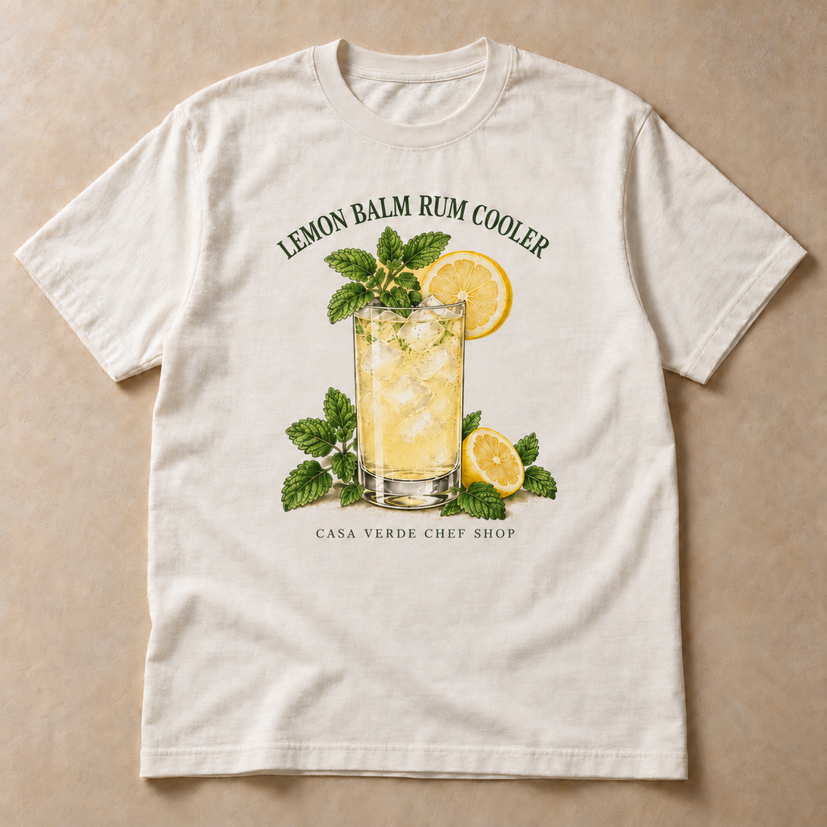 Lemon Balm Rum Cooler T-Shirt — approved individual front design preview with an illustrated tall cocktail glass, lemon wheels and leafy lemon balm and the Casa Verde Chef Shop signature. Illustrative garment mockup, not a production master.