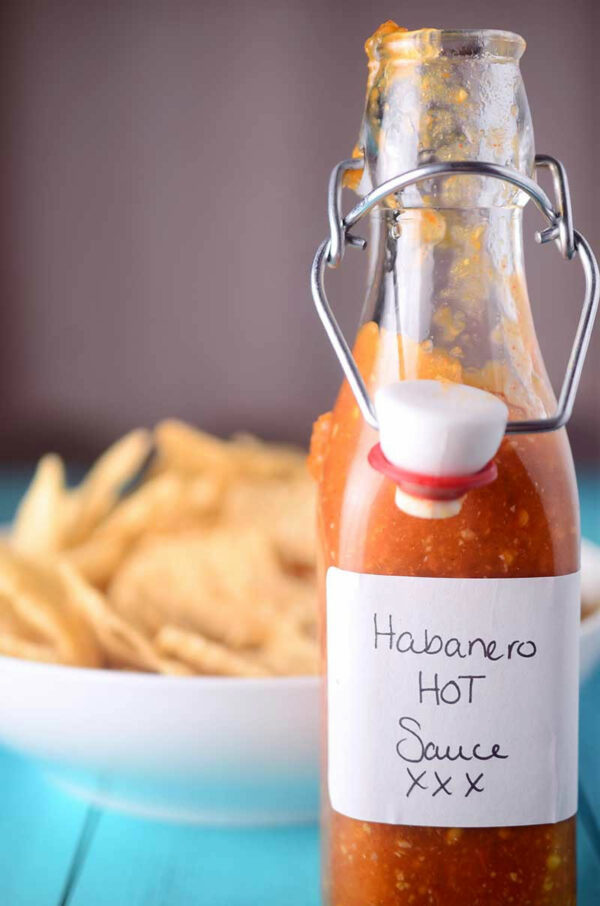 Bottle of habanero hot sauce with a label, placed on a surface with a blurred background.
