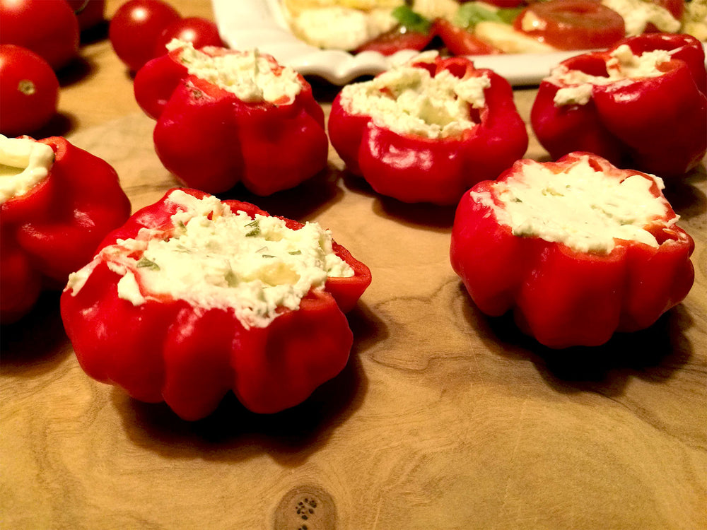 Red Stuffing Scotch Bonnet peppers stuffed with a white filling on a wooden surface